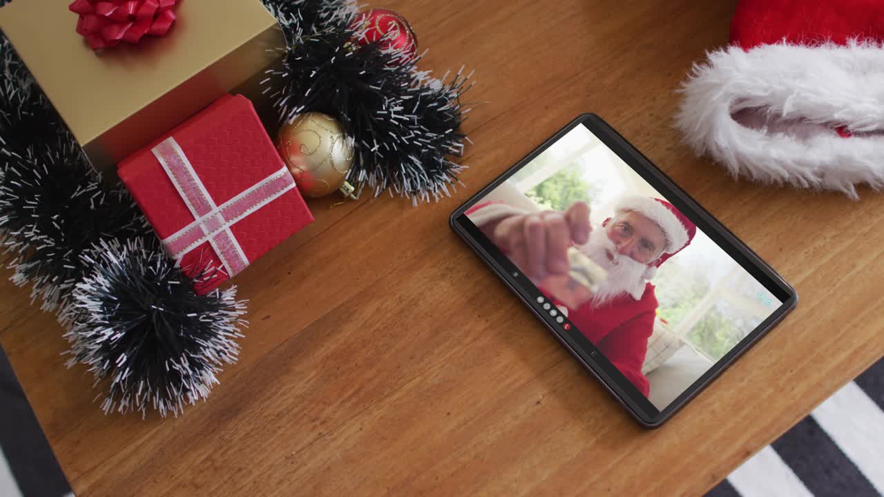 穿着圣诞老人服装的微笑白人男子在平板电脑上进行圣诞视频通话视频下载