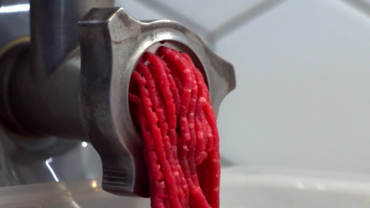 近距离视频绞肉机与切碎的肉滚动出来。慢动作视频，肉末加工视频素材