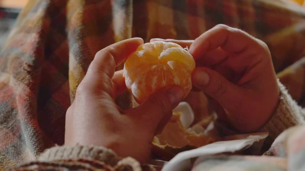 一个女人吃橘子在一个舒适的室内环境与格子花呢视频下载