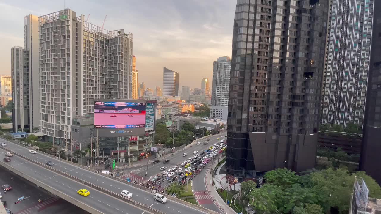曼谷的城市景观(罗摩9十字路口)日落-黄昏时橙色的天空，摩天大楼和高速公路。视频下载