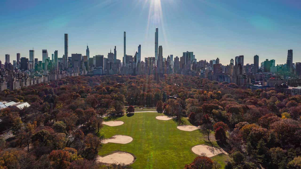 在阳光明媚的日子里，中央公园上空有秋色的树木。以市中心摩天大楼为背景的大范围超特写。美国纽约曼哈顿视频下载