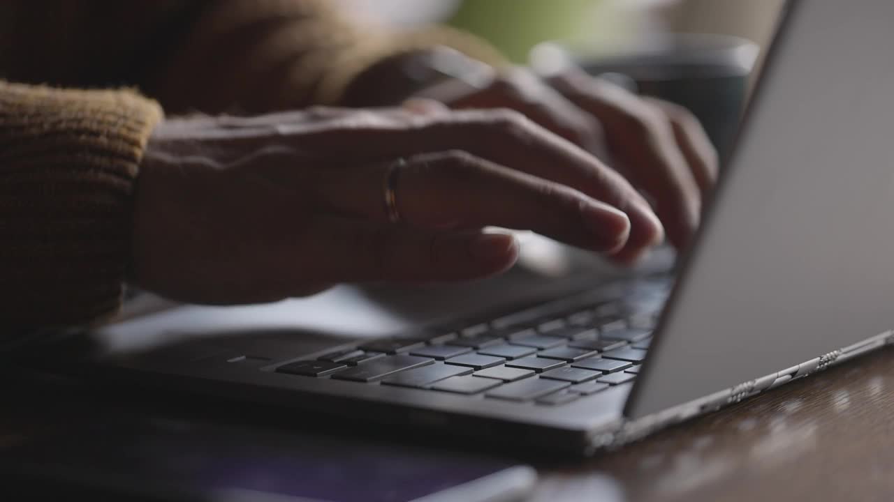男人的手在笔记本电脑键盘上打字。他在工作中使用网络技术。慢镜头特写,视频素材
