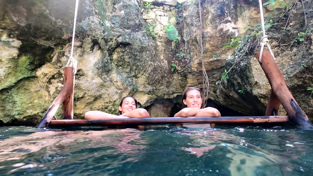 中景:女朋友们在丛林中的生态度假胜地的天然井里开怀大笑视频下载