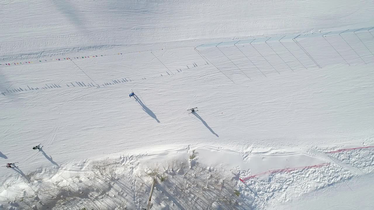 在晴朗的冬日里，滑雪者沿着滑雪坡向下的空中俯瞰。无人机跟踪滑雪者视频素材