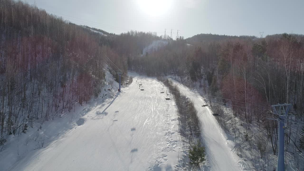 吊椅在斜坡上移动的鸟瞰图。在晴朗的冬日，从山上下山的滑雪者视频素材