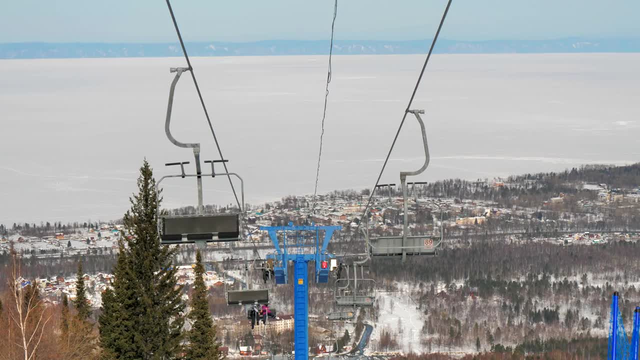 在晴朗的天气里，滑雪缆车索道在白雪覆盖的山坡和树木上缓缓移动。视频素材
