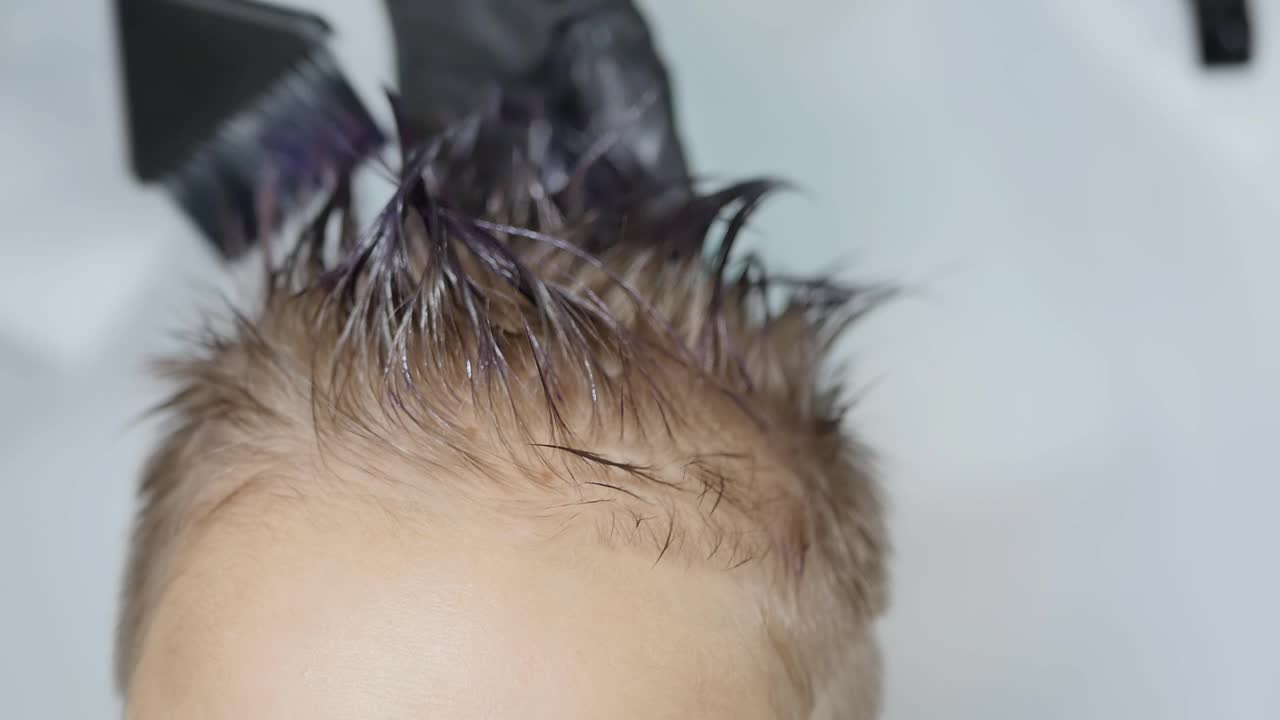 美发师用刷子和手将染发剂涂抹在顾客的头发上视频下载