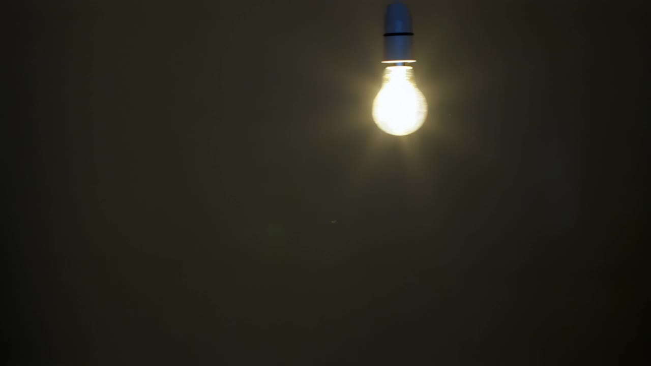 灯泡在黑暗中摆动。视频素材