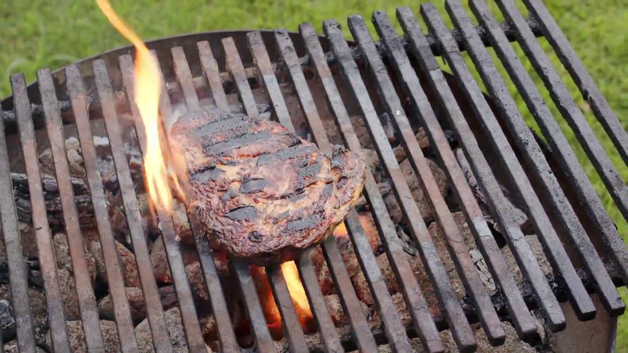 将调味的肋眼牛排放在烧烤架上，用大火翻炒。4 k慢动作。视频素材