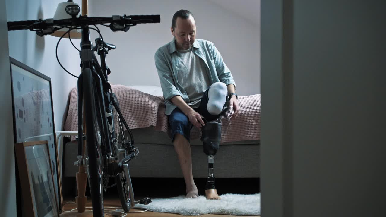 成熟的男人戴着假腿，从家里的卧室拿出自行车视频下载