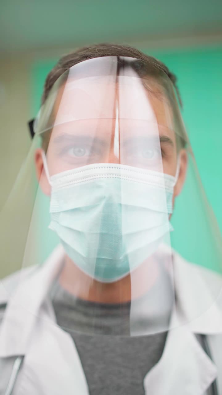 冠状病毒医生在防护面罩和口罩看着相机视频下载