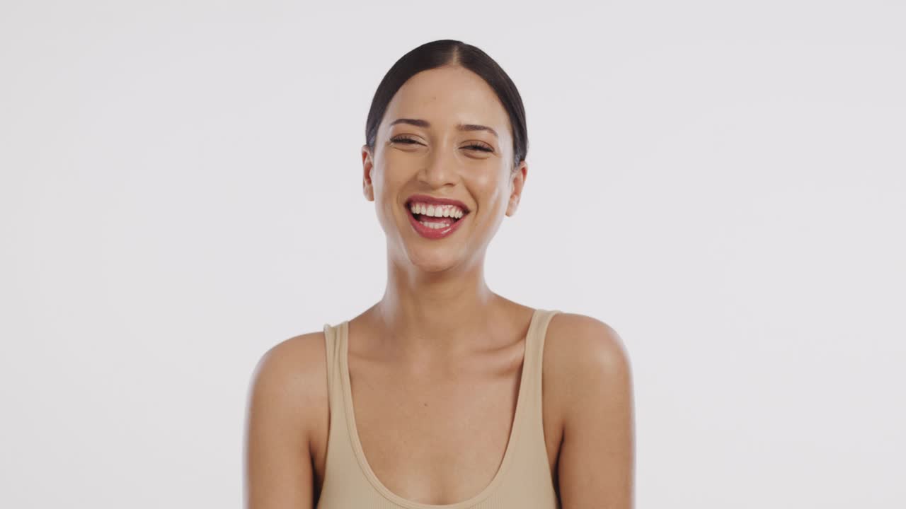 一个美丽的年轻女子站在白色背景下大笑的4k视频片段视频素材