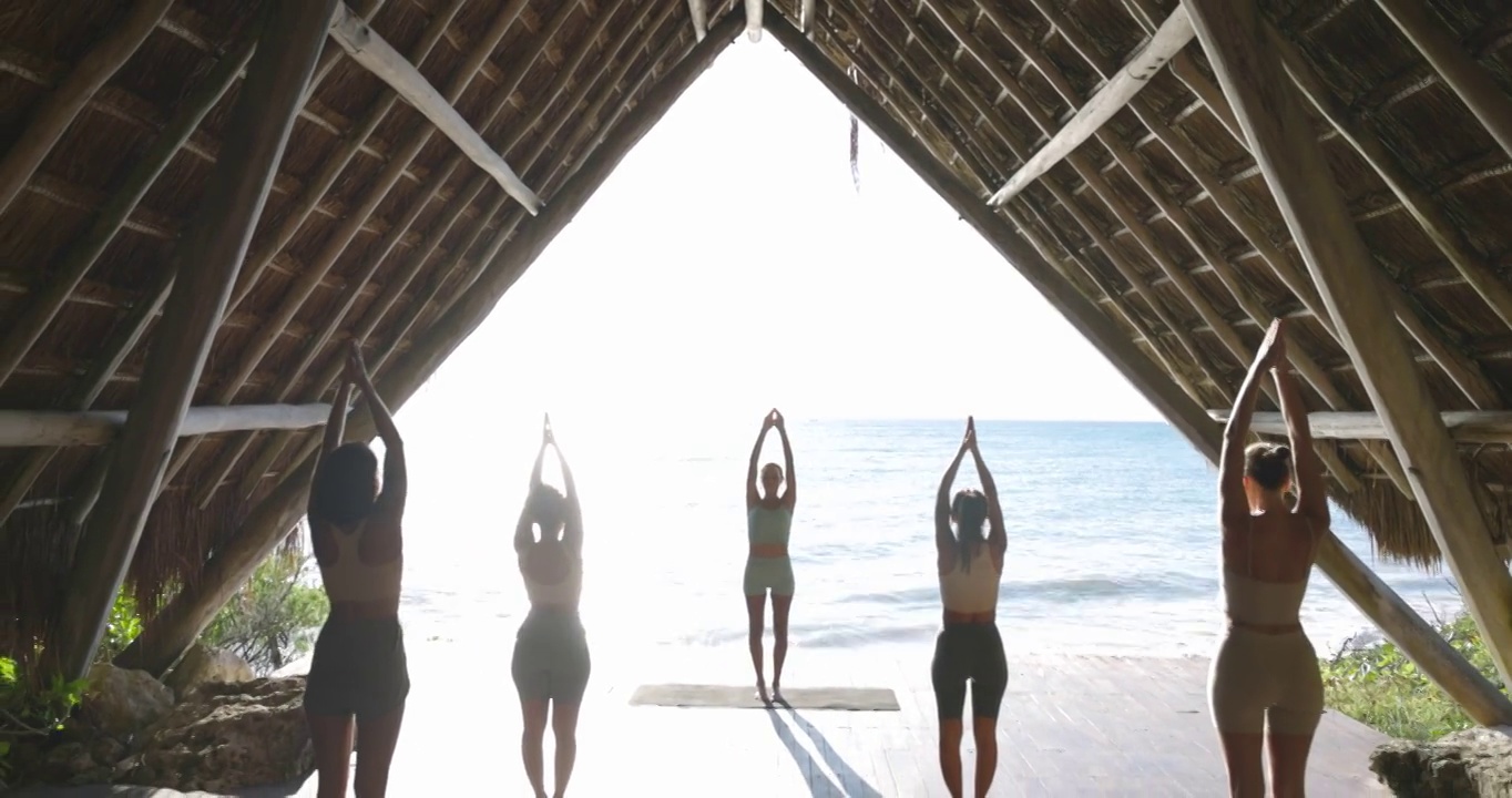 在热带度假胜地的海滨凉亭练习瑜伽的妇女在课堂上的宽镜头视频素材