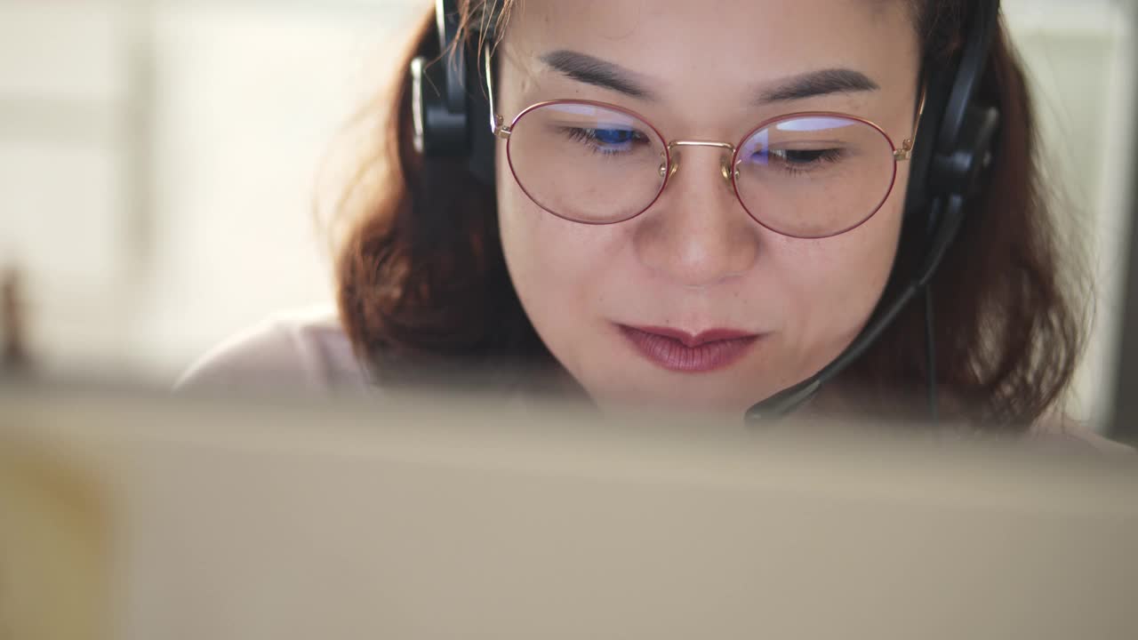 一个女人在办公室里使用电脑和耳机，特写视频素材