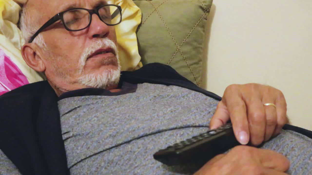 一个老人在看电视的时候在沙发上睡着了视频素材