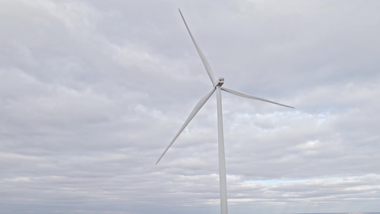 旋转风车在阴天背景。无人机俯瞰，清洁的可再生能源由风力涡轮机产生。在海上或野外的大农场全速旋转叶片。另一种生活方式视频素材