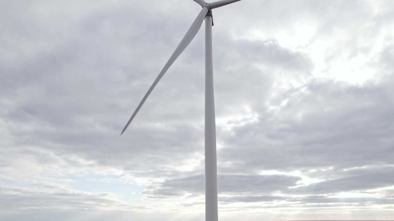 旋转风车在阴天背景。无人机俯瞰，清洁的可再生能源由风力涡轮机产生。在海上或野外的大农场全速旋转叶片。另一种生活方式视频素材