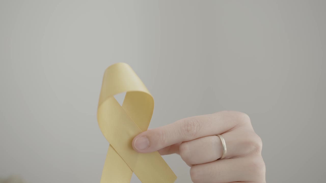 手握黄色金丝带，肉瘤意识，骨癌意识，儿童癌症意识，世界自杀预防日，9月黄色视频下载