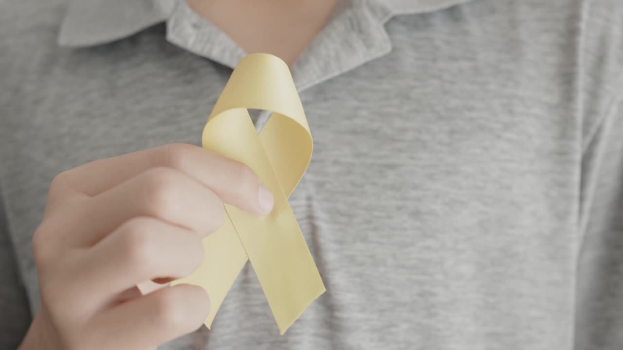 手握黄色金丝带，肉瘤意识，骨癌意识，儿童癌症意识，世界自杀预防日，9月黄色视频素材