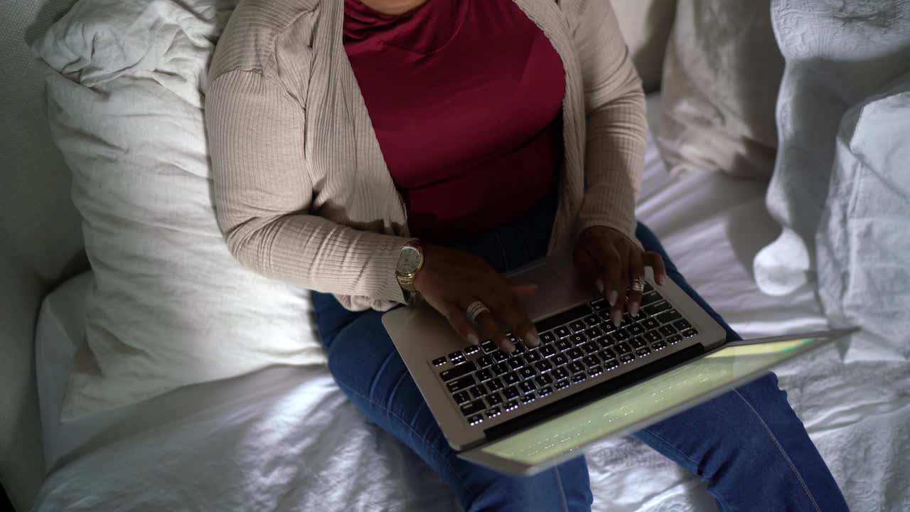 成熟的女人在家里的床上使用笔记本电脑视频素材