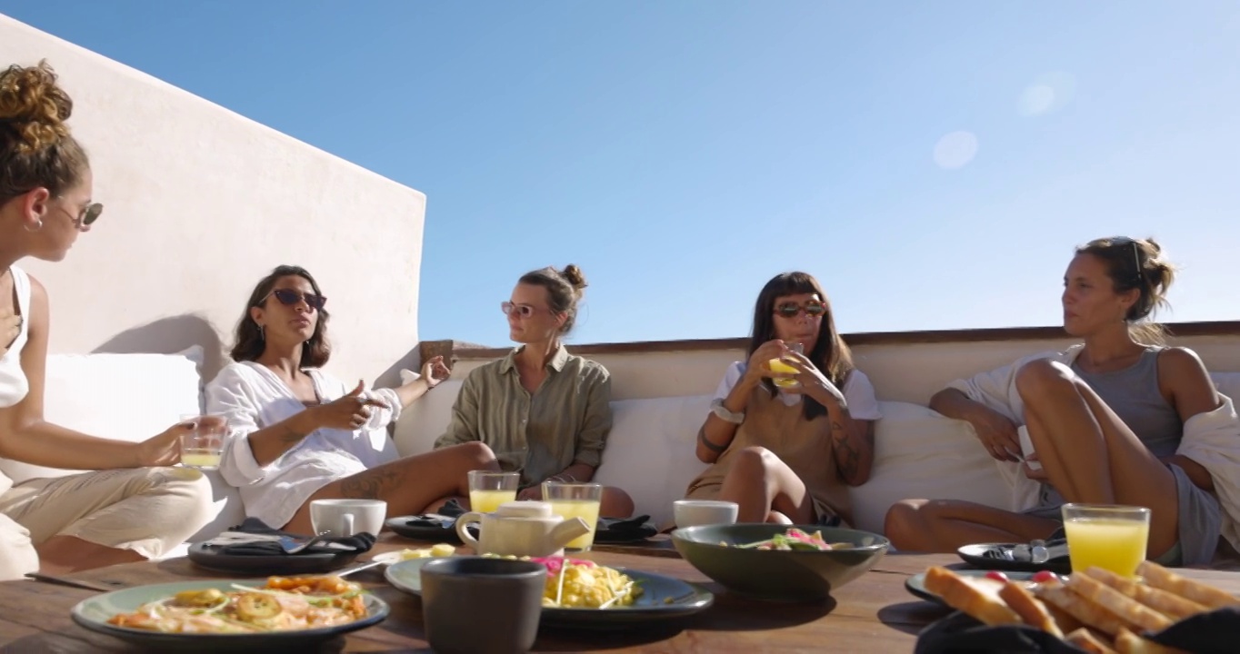 在热带度假胜地的豪华套房甲板上放松的女性朋友的广泛镜头视频下载