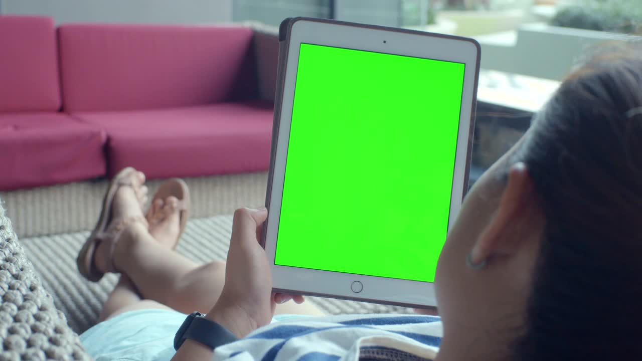 一个年轻女子在酒店大厅坐在沙发上使用绿色模型屏幕的智能手机视频素材