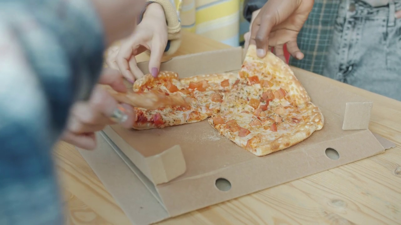 在办公室里吃东西时，男人和女人的手拿着披萨的特写视频素材