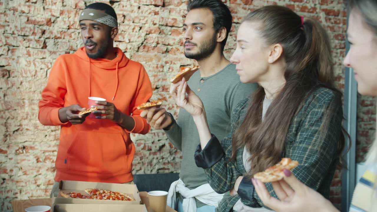 在现代共享办公室里，快乐的男男女女们享受着披萨，畅谈着视频素材