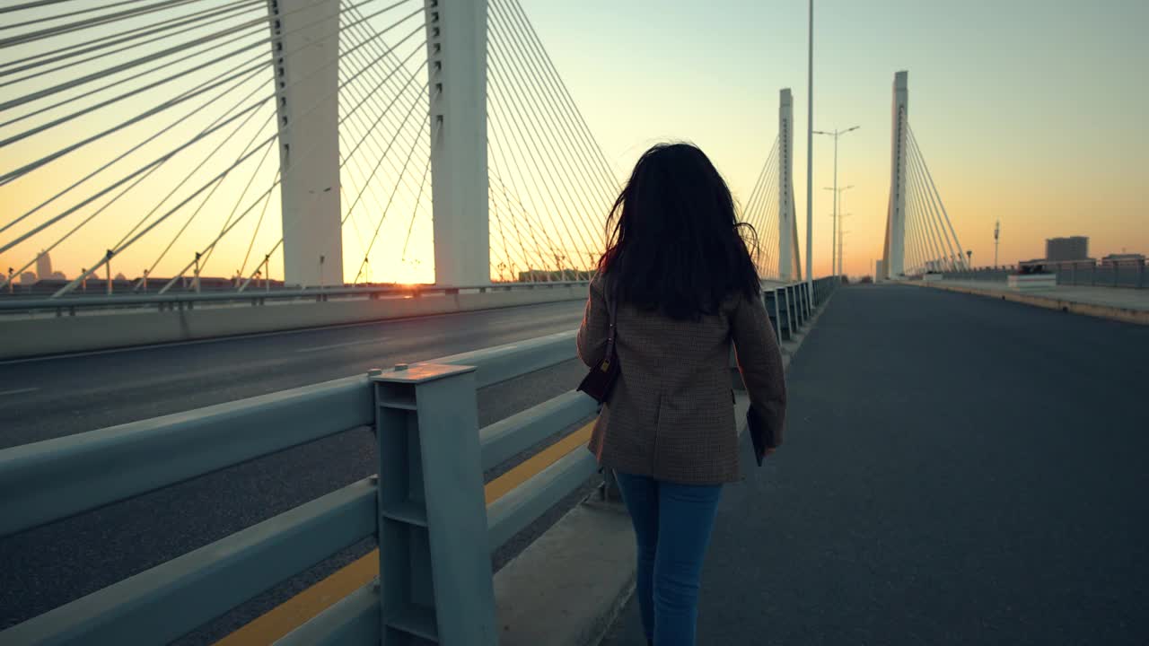 日落时分，一个女人走在桥上视频素材