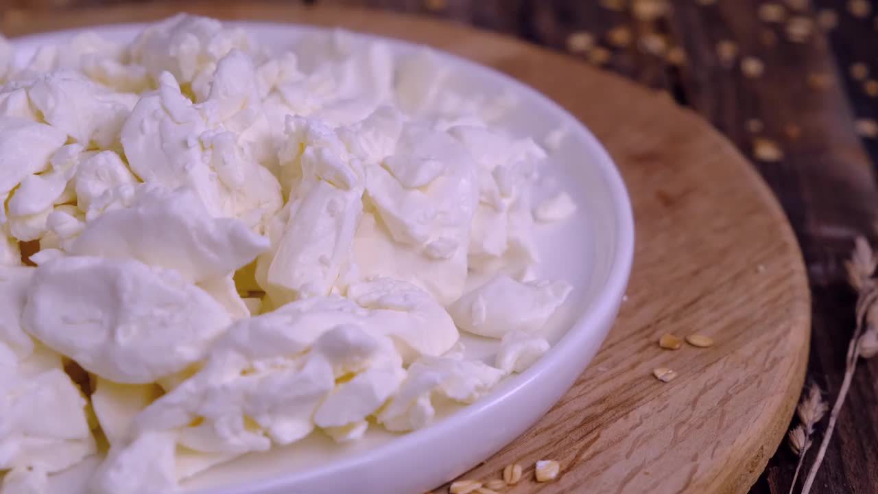 白盘子上的白干酪在木制背景上的特写镜头视频素材