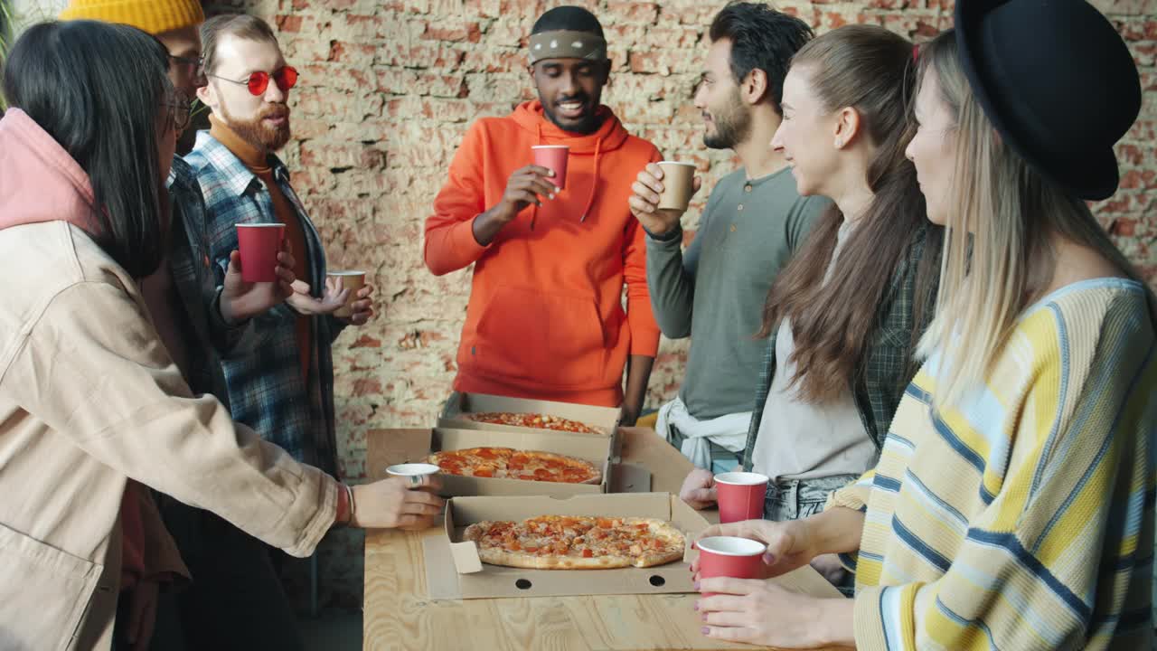 多民族的商人在现代loft风格的办公室里一起吃披萨视频素材