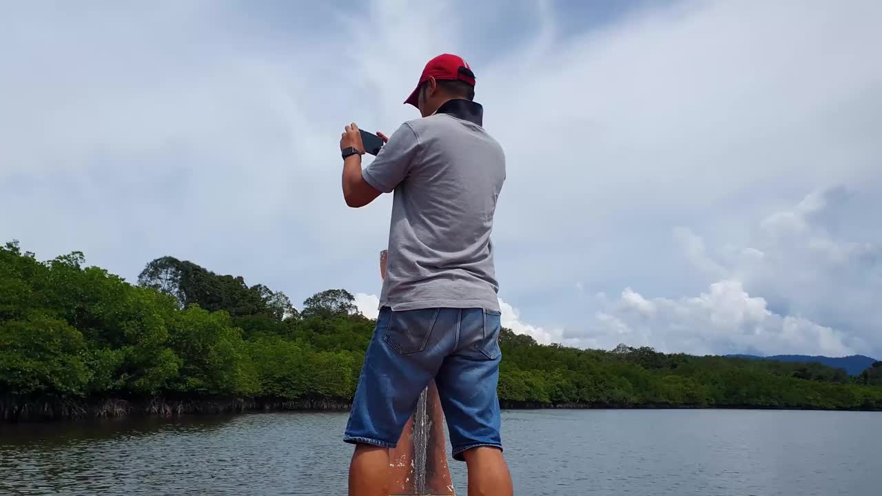男人站在船上，河景红树林森林之旅视频下载