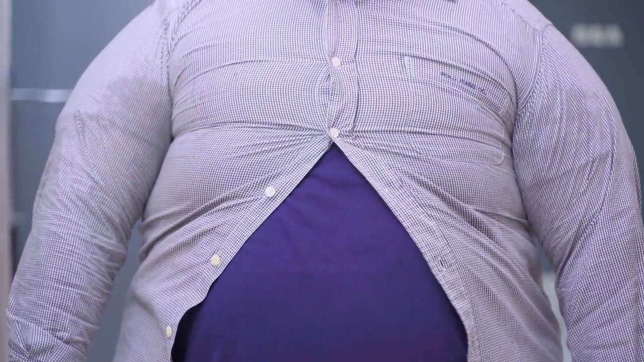 一个肥胖的男人正试图扣上衬衫扣子视频下载
