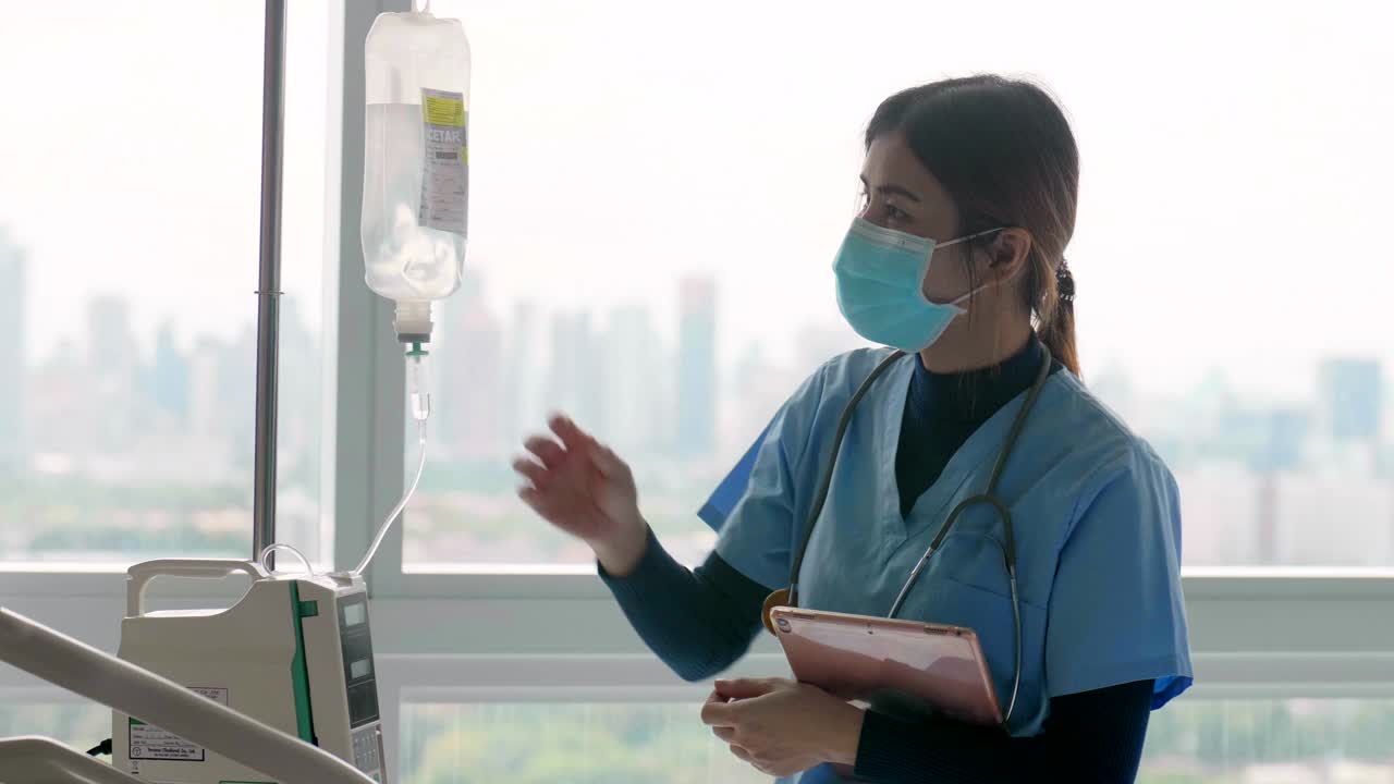戴口罩的护士检查病人的生命体征，静脉输液袋视频素材