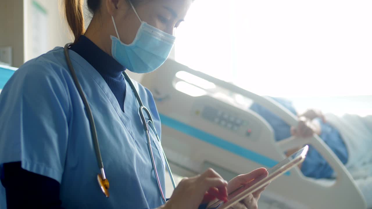 戴口罩的护士检查病人的生命体征，静脉输液袋视频素材