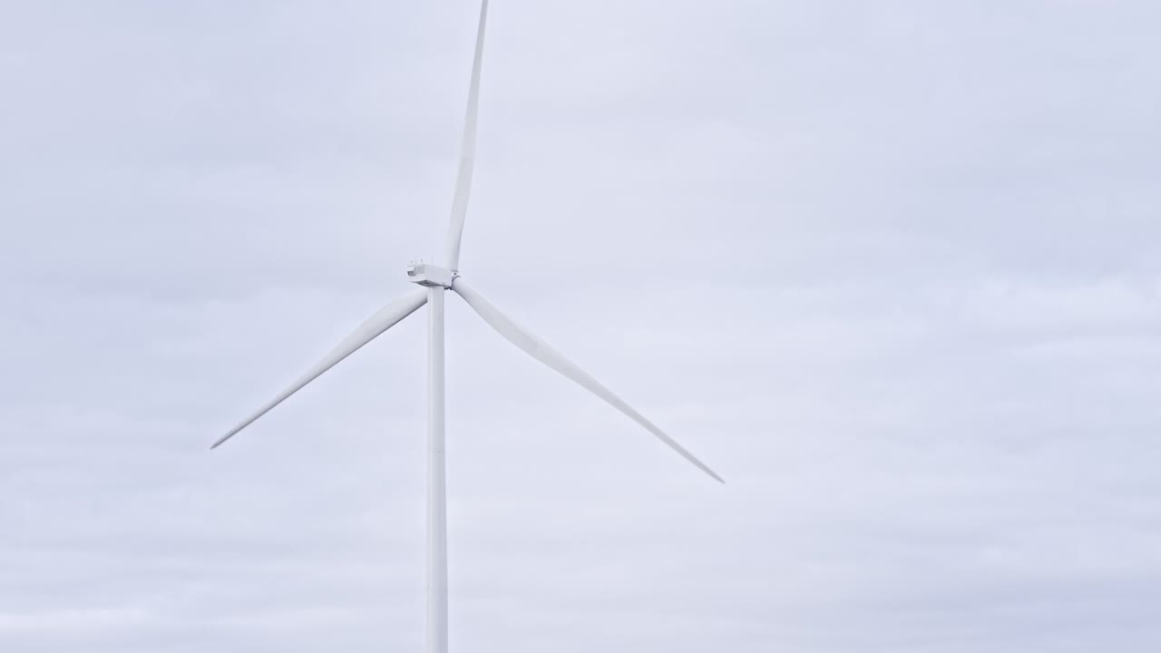 在海上或野外的大农场全速旋转叶片。旋转风车在灰色天空的背景。由风力涡轮机产生的清洁可再生能源。另一种生活方式视频素材
