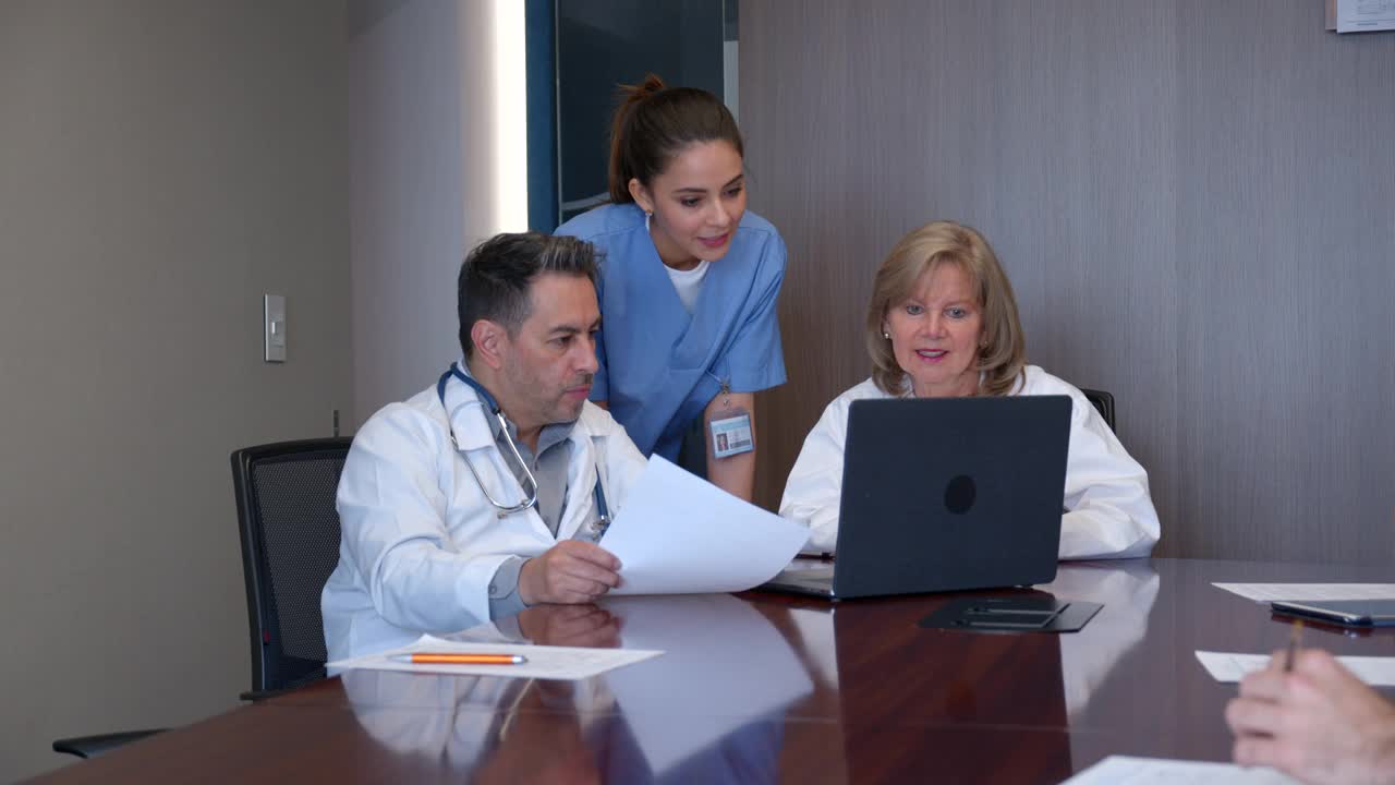 医生和护士小组讨论一个病例，同时在笔记本电脑上查看病人的病历视频下载