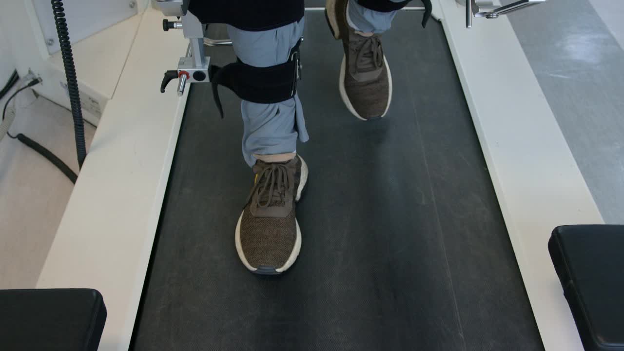 近无法辨认的残疾患者行走在跑步机上与动力外骨骼的帮助视频素材