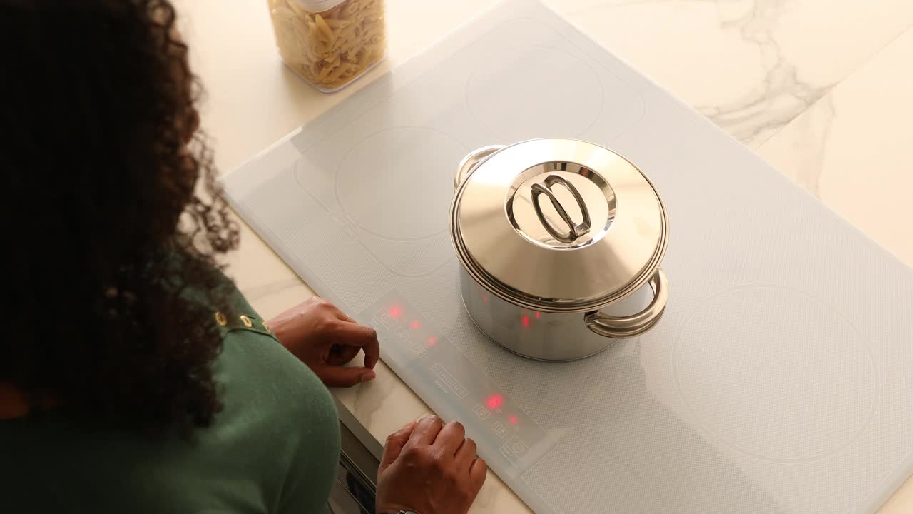 在智能感应炉灶上，一名妇女正在将意大利面放入沸水中煮视频下载