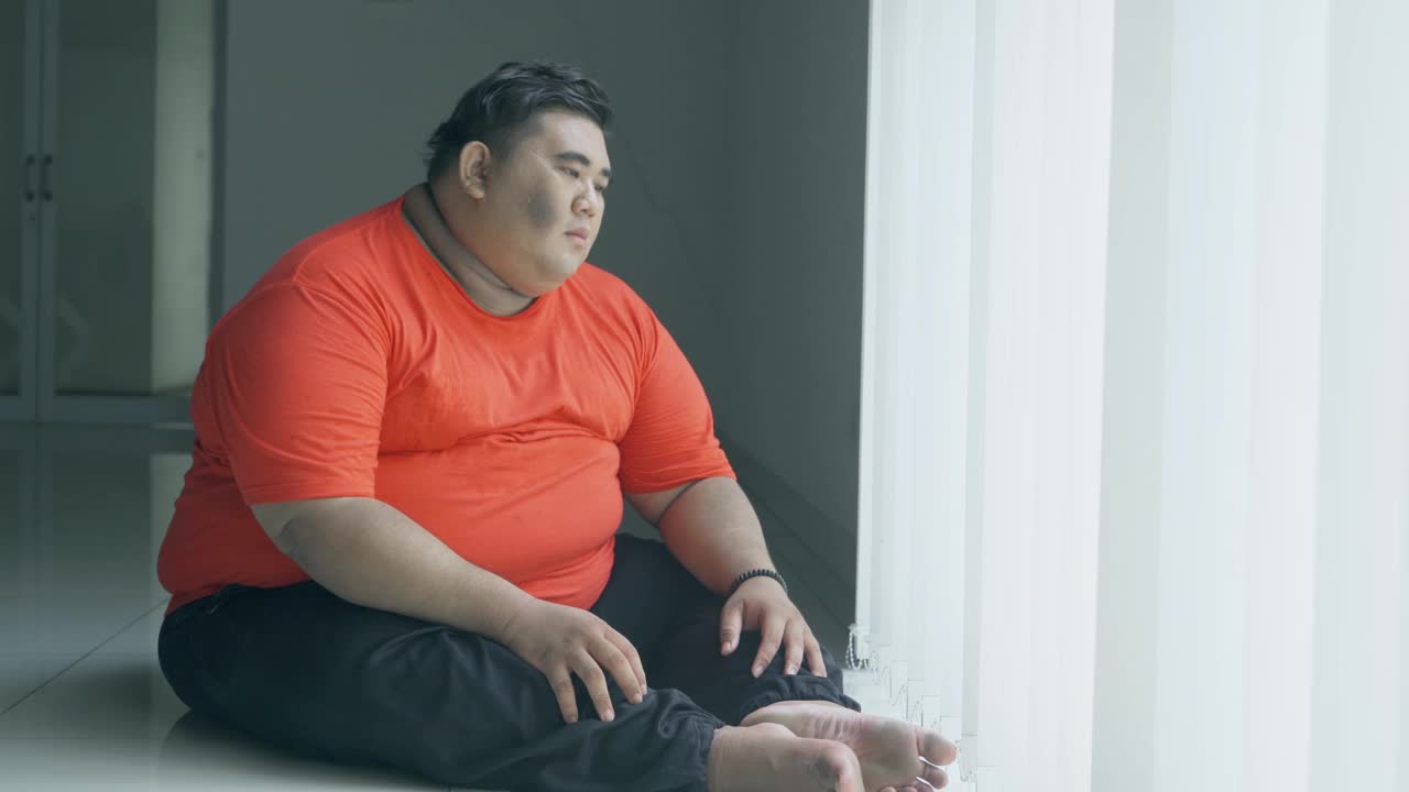 一个胖男人在窗边忧郁地做着白日梦视频素材