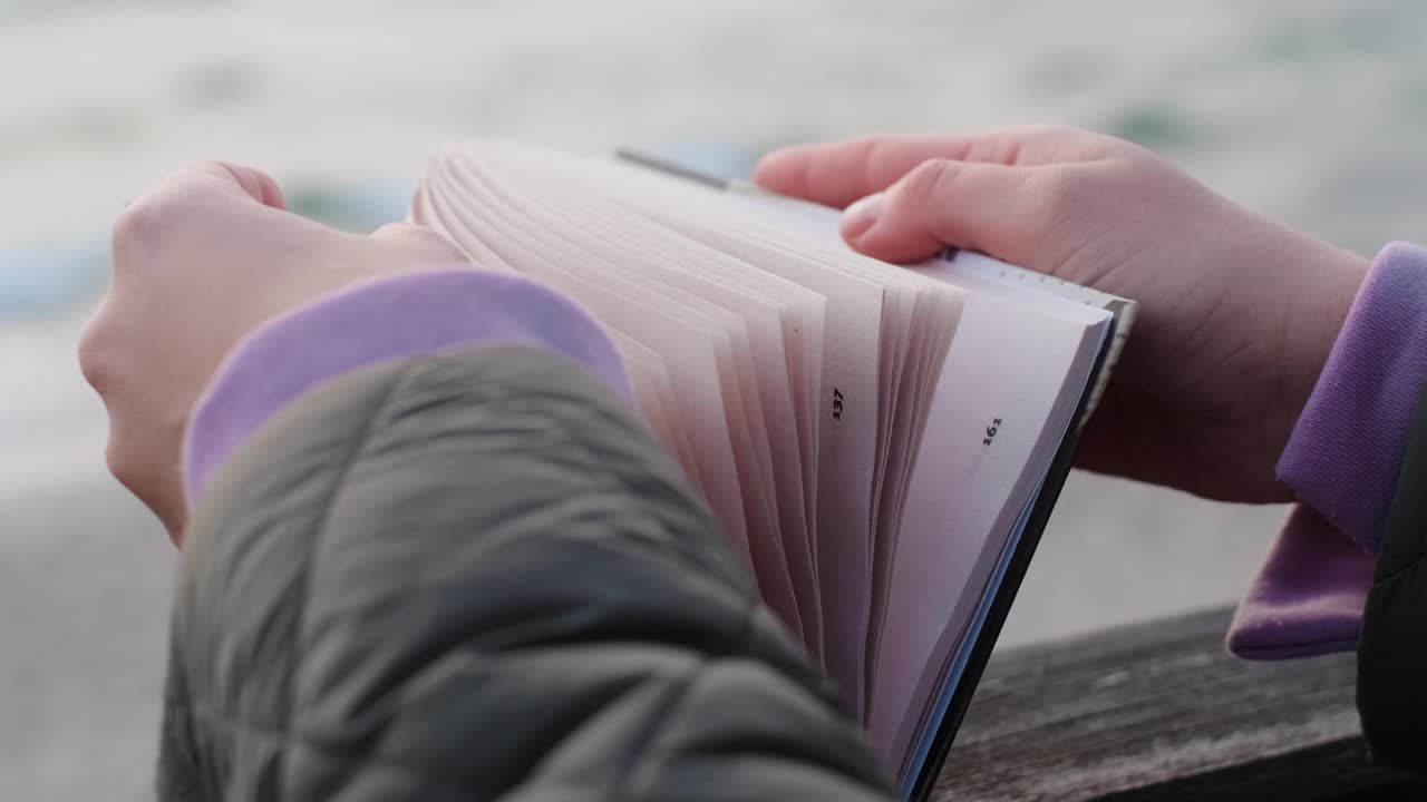 风以慢动作翻动书页。打开的书躺在海边的长椅上，4k 60p视频素材