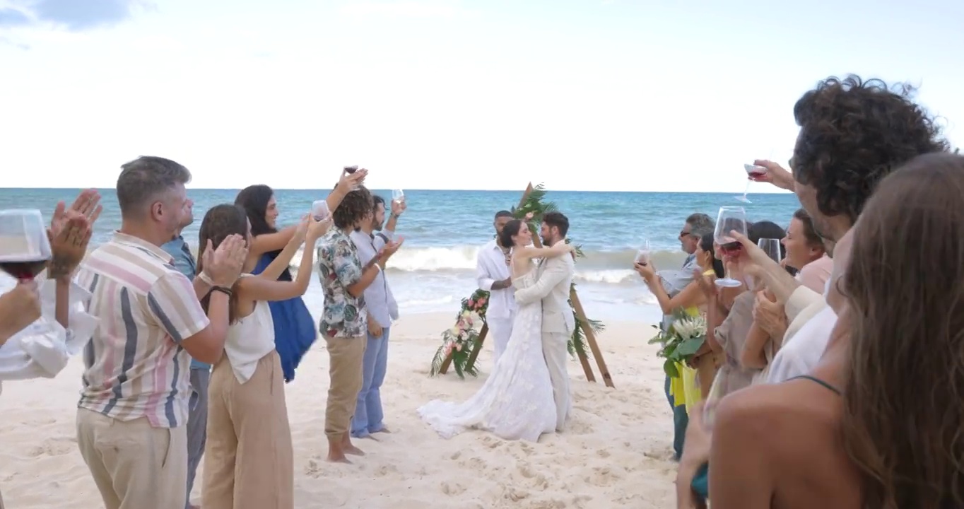 新娘和新郎在朋友和家人面前在热带海滩上结婚的广角镜头视频下载