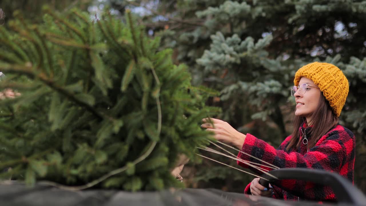 年轻夫妇把他们的新圣诞树绑在汽车屋顶上视频下载