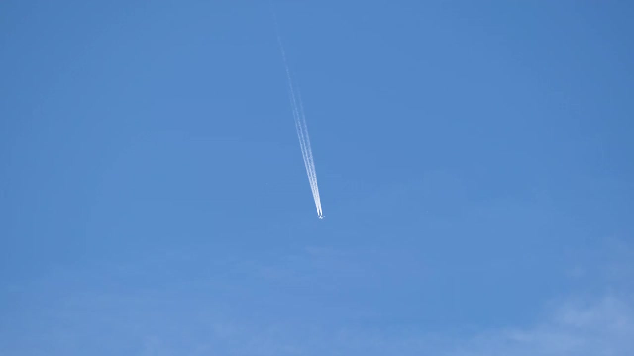 远处的喷气式客机在晴空万里的高空飞行，留下白色的烟雾和尾迹。航空运输的概念视频素材