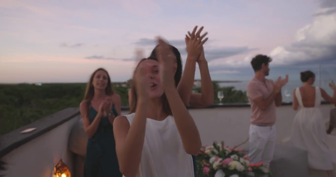 在热带度假胜地，朋友和家人在日落时分庆祝婚礼后的屋顶派对视频下载