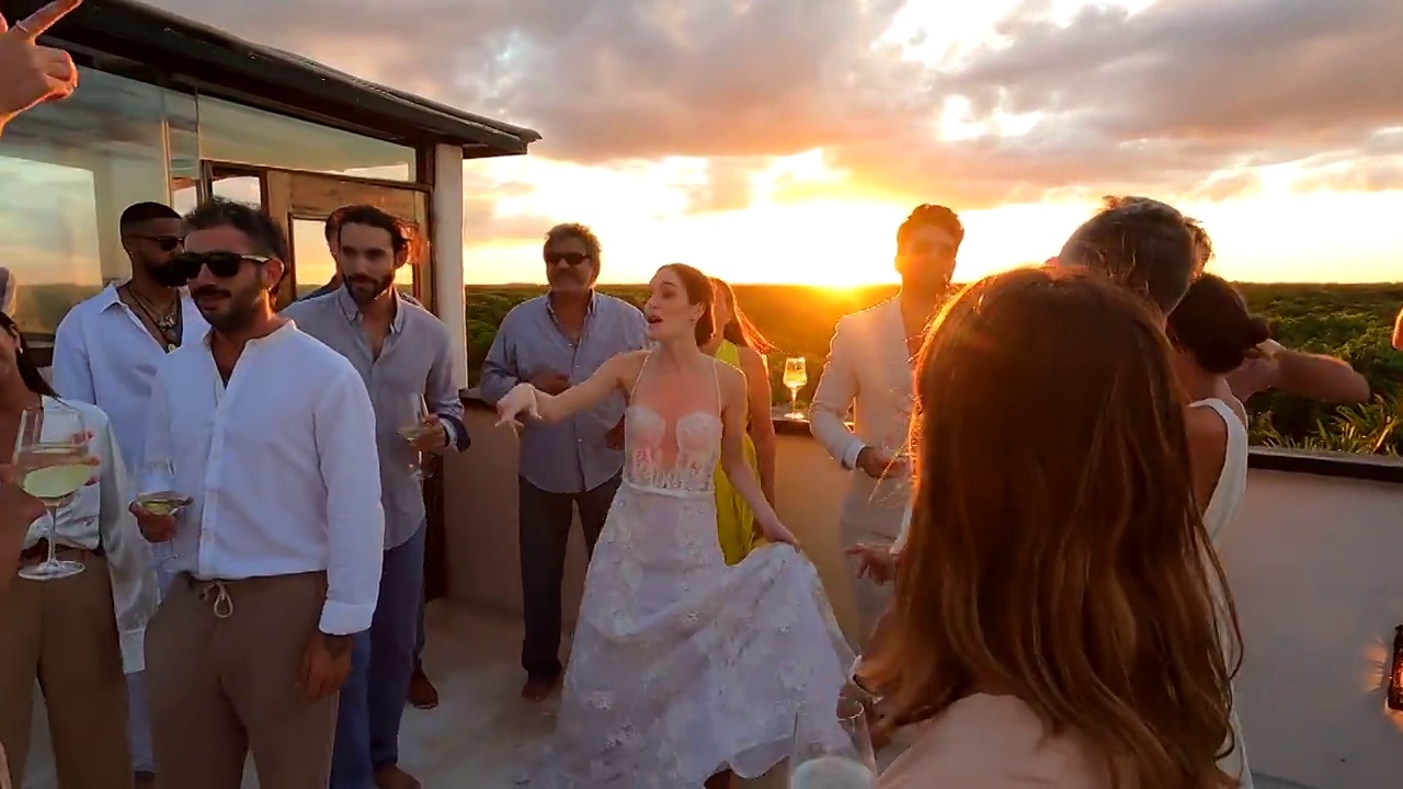 在热带度假胜地的婚礼结束后，微笑的新娘跳舞，和朋友们在日落时分的屋顶甲板上庆祝视频下载