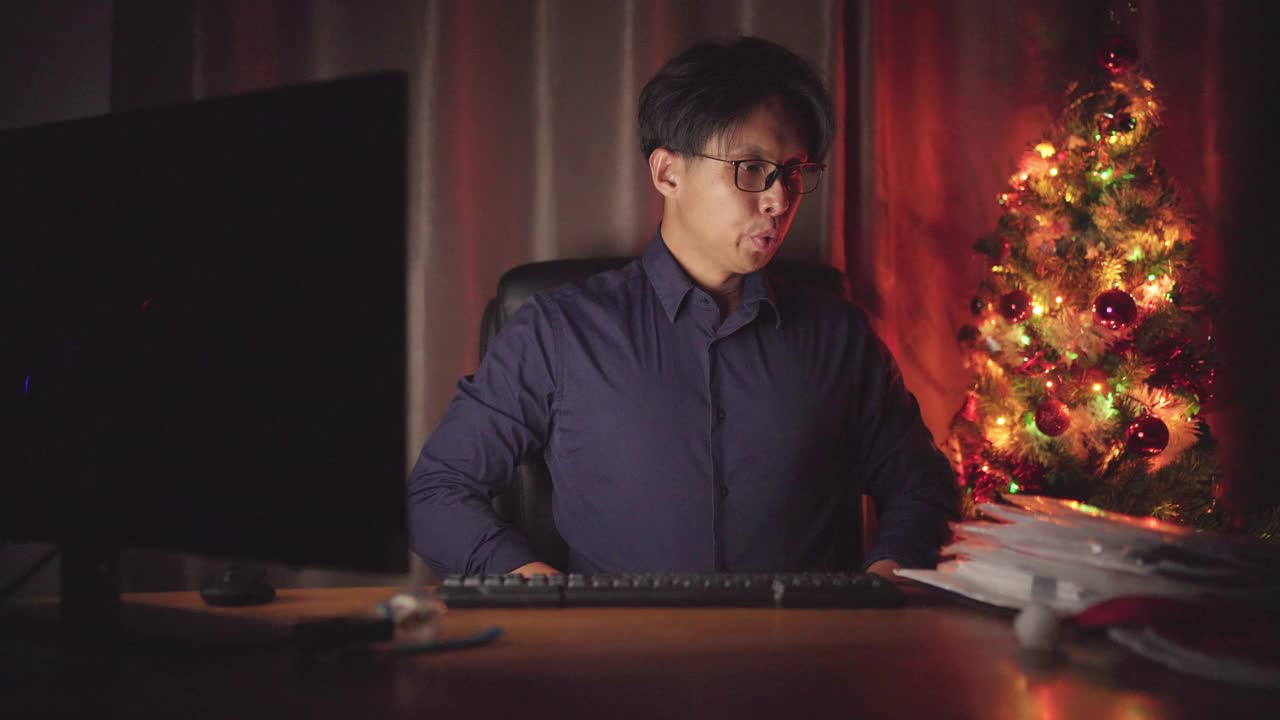 亚洲男人在新年的晚上在办公室工作到很晚的时候感到困倦视频下载