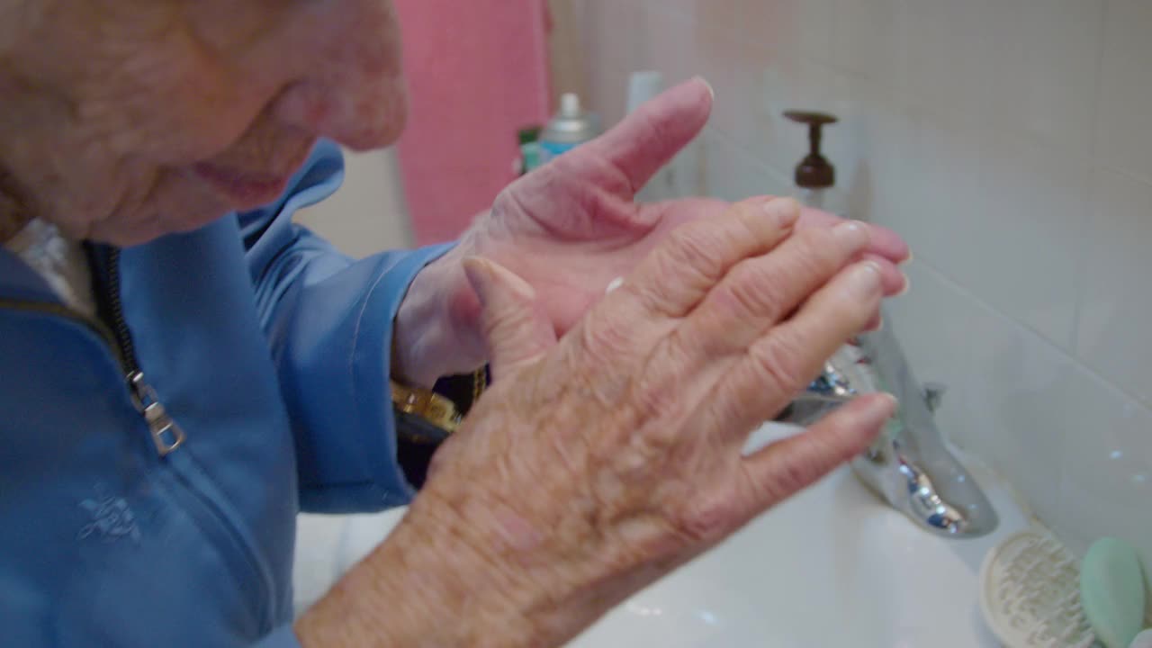 一位100岁的老妇人在浴室的水槽上擦手润肤霜视频下载