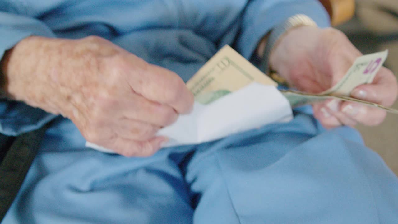 一位年长的白人妇女从一个信封里数一叠现金视频下载