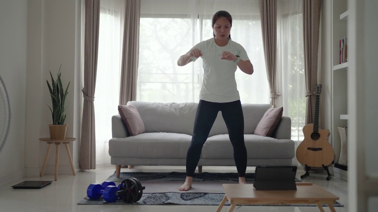 女性在家里用平板电脑锻炼和练习脂肪燃烧视频下载